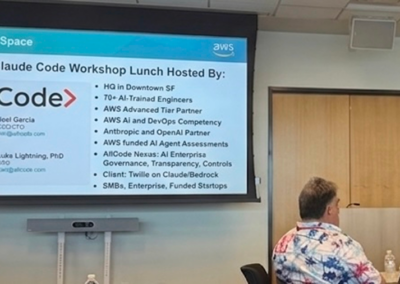 Participants getting started with the hands-on Claude Code workshop, with Welcome screens displayed on dual monitors